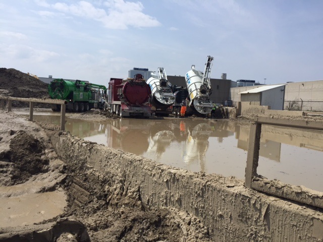 maintenance trucks dumping wastewater and sludge in holding pond