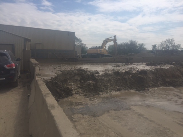 holding pond full of mud with excavator in background