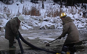 workers using industrial vacuum for tailings recovery in pond